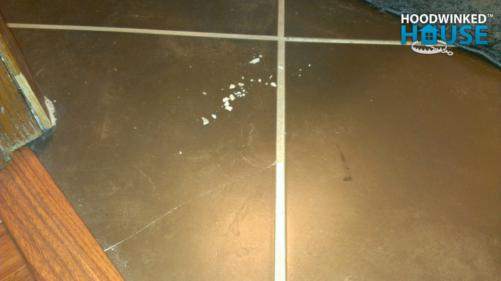 Cracked bathroom tile with flakes of grout