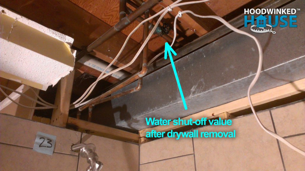Demolished bathroom ceiling showing a water shut-off valve hidden behind drywall.