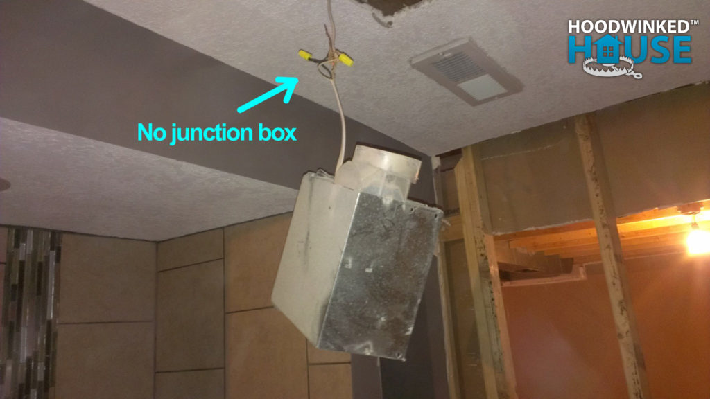 Bathroom fan housing dangling from spliced wires, no junction box.