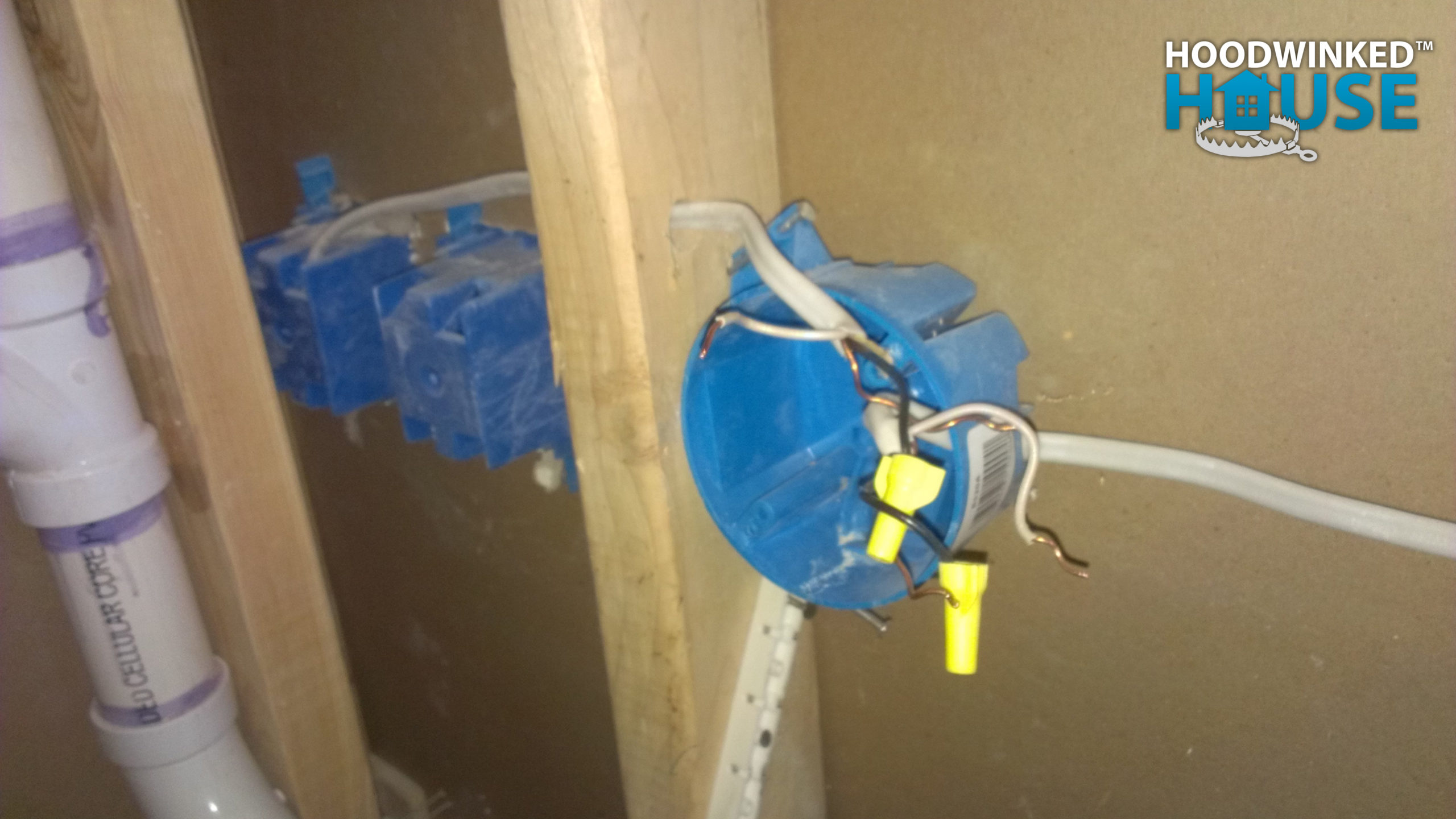 A round ceiling junction box was used inside wall framing and illegally hidden behind drywall.