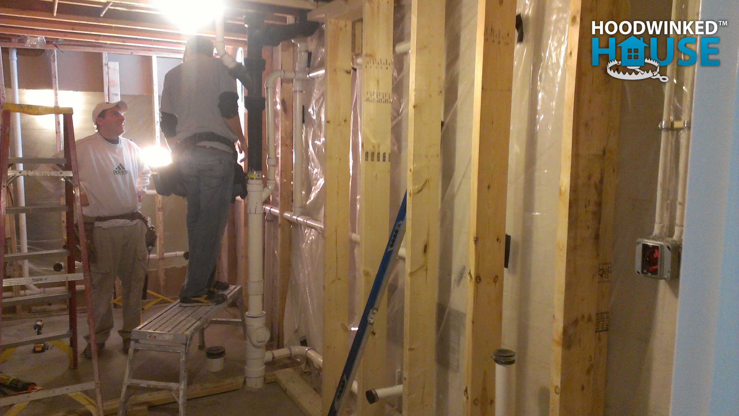 Carpenters use ladders and scaffolding while erecting new basement framing.