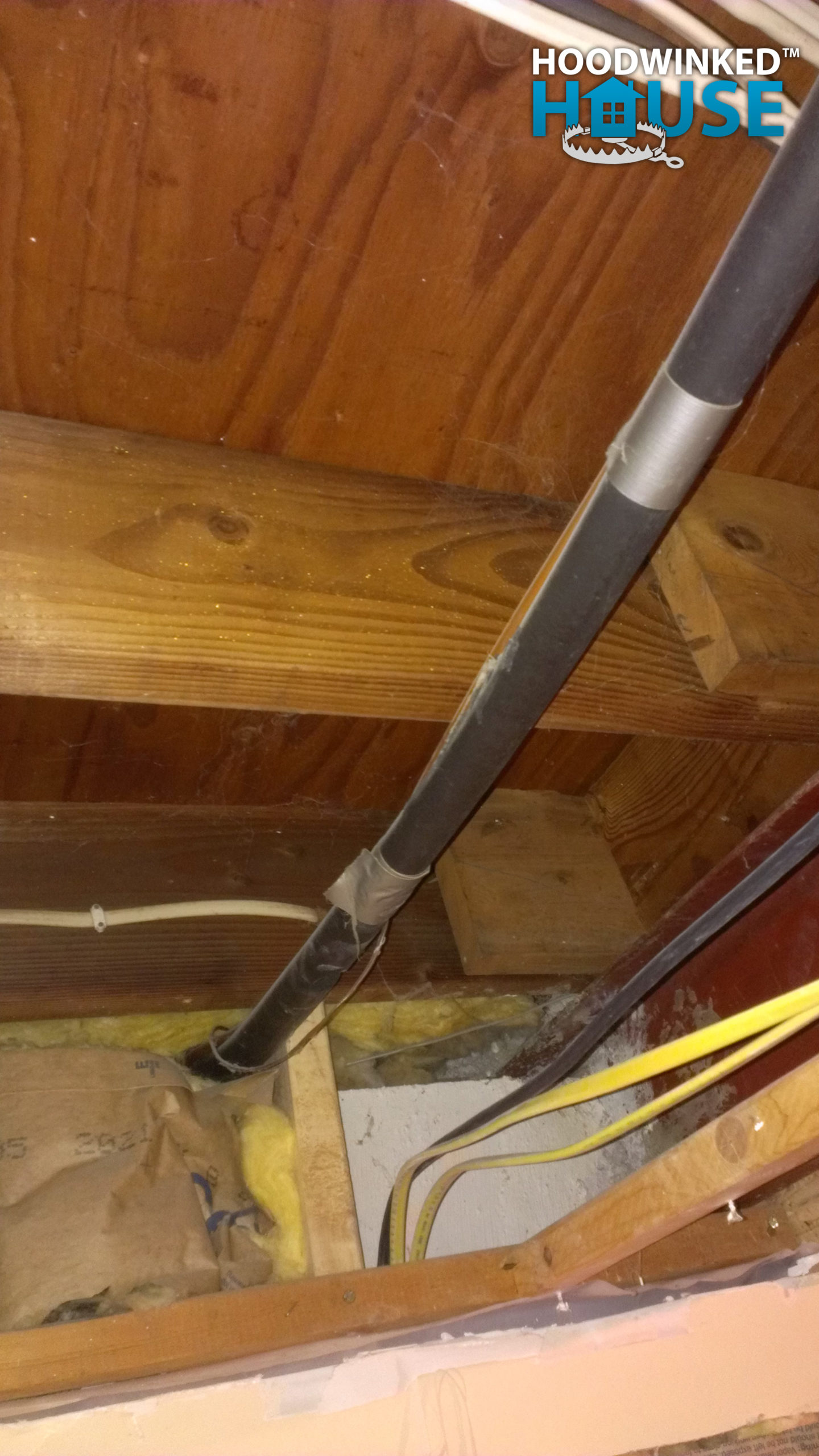 Insulated air conditioner line runs across a basement ceiling and through a foundation wall.