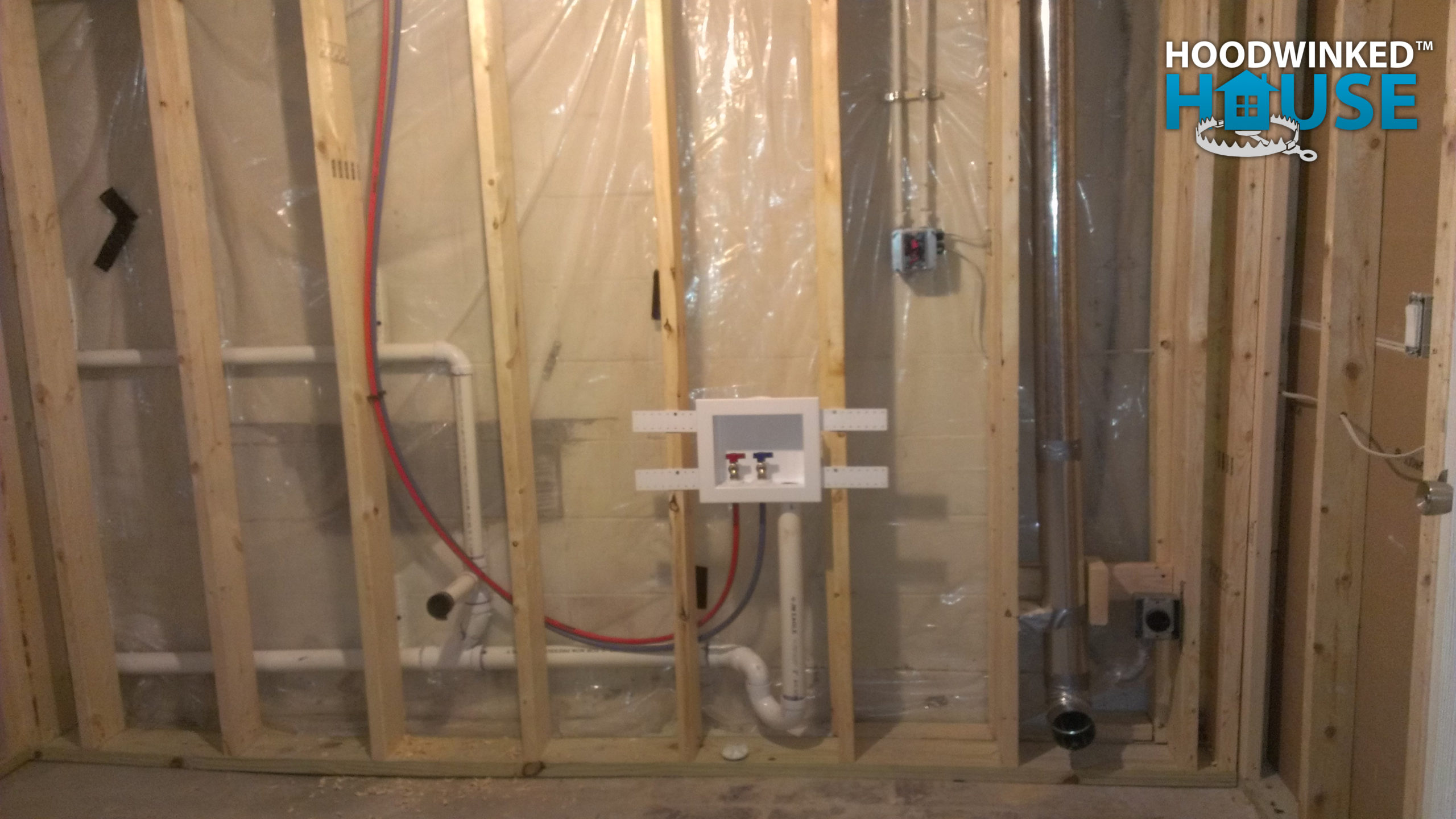 Laundry room framing with plumbing and a dryer vent.