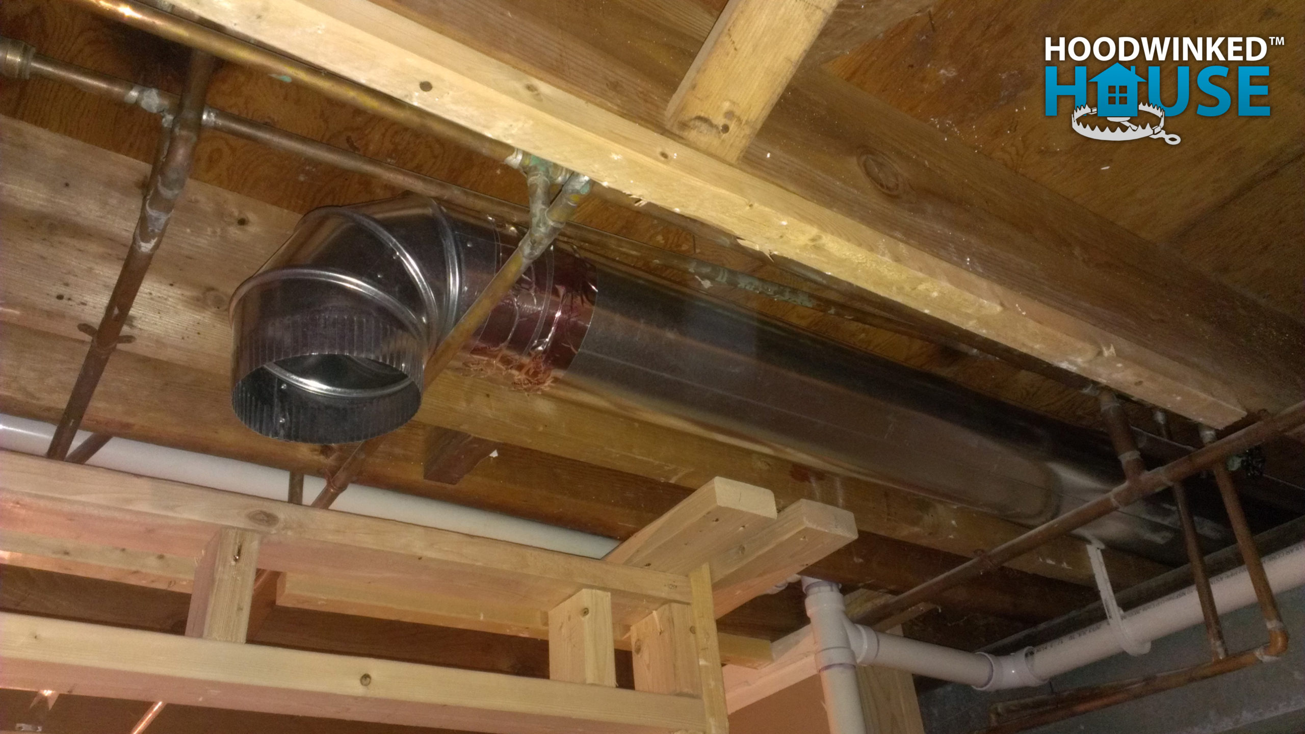 An basement ceiling air duct branch ends in an elbow.