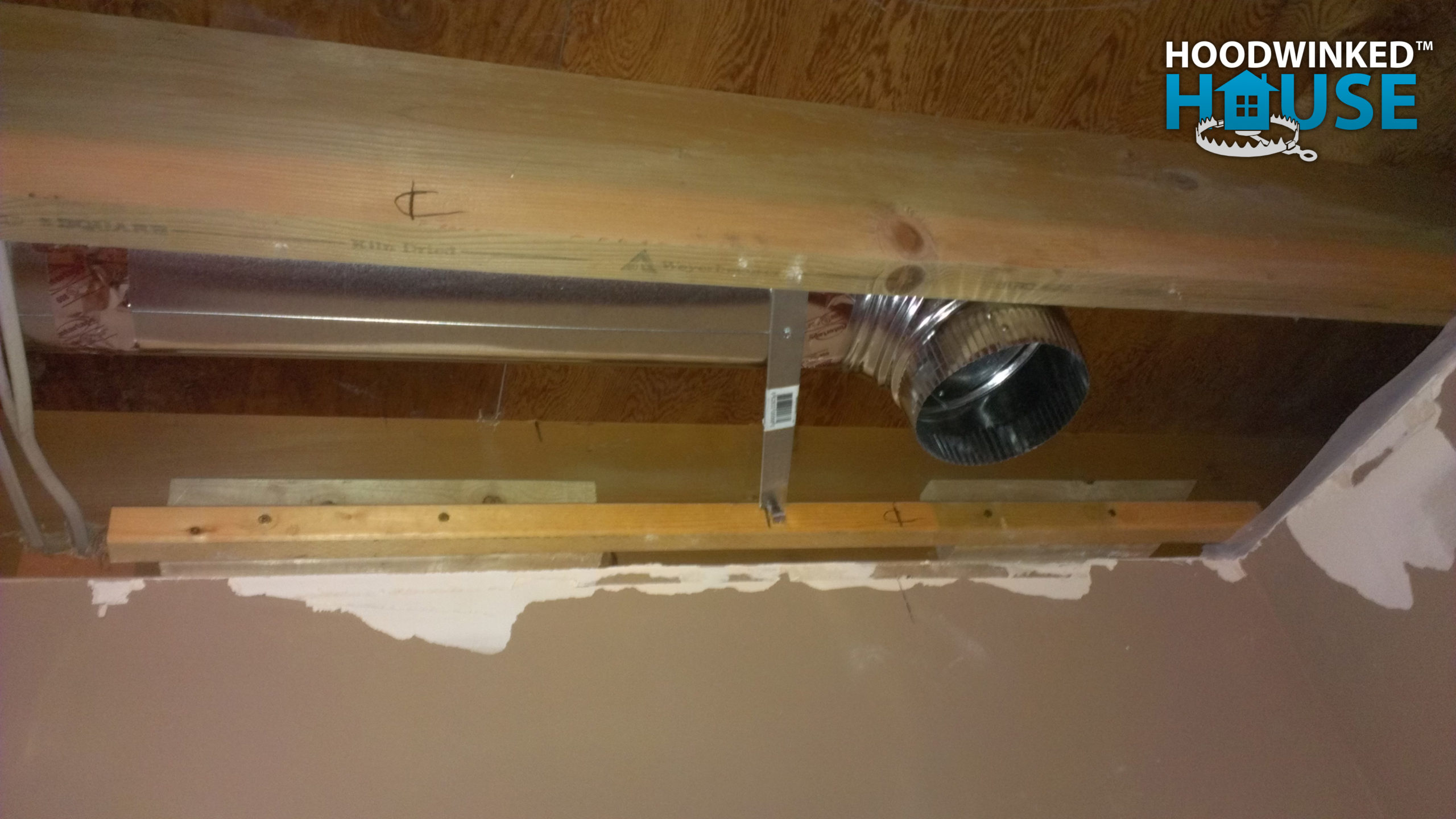 An basement ceiling air duct branch ends in an elbow.