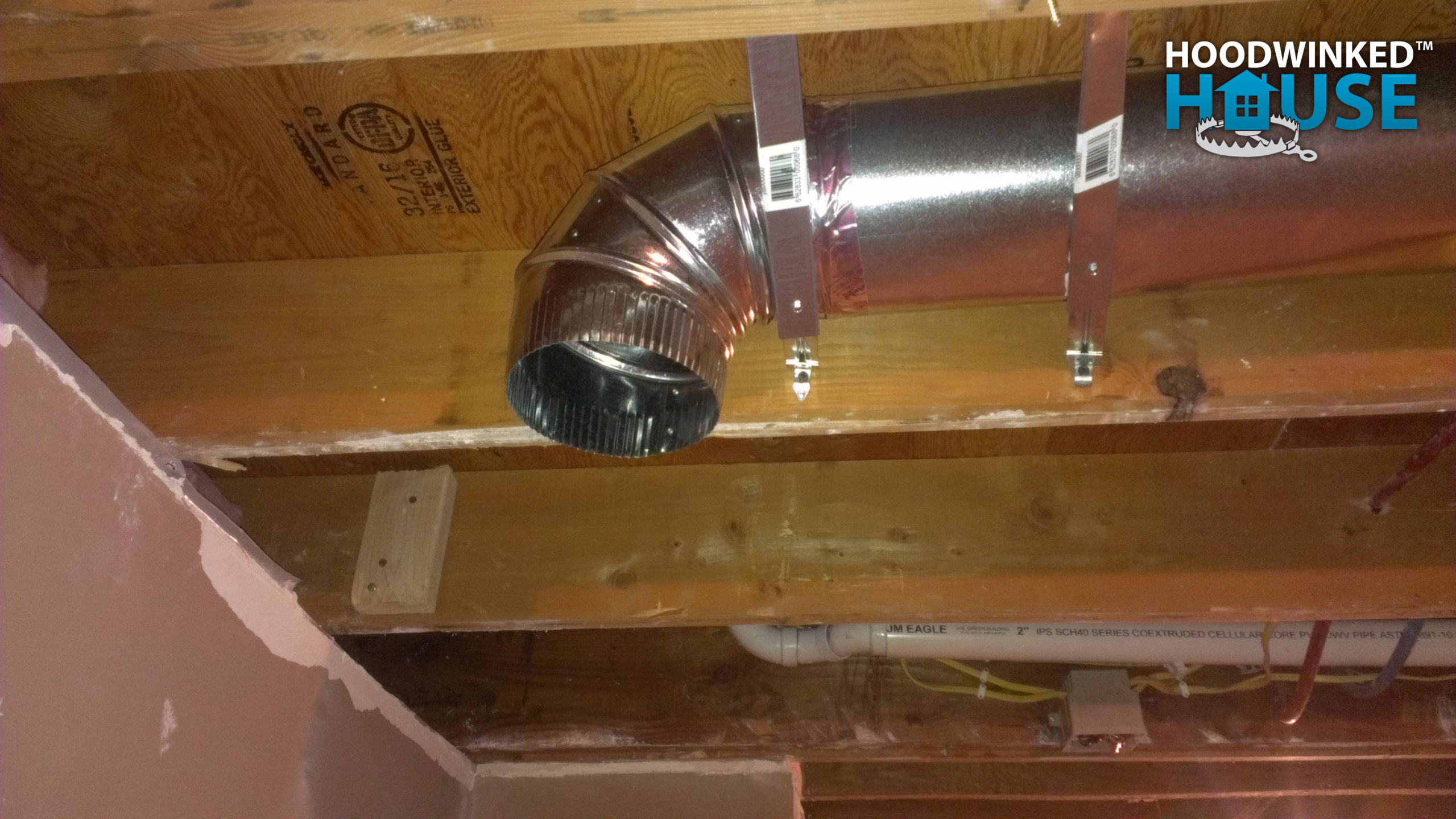An basement ceiling air duct branch ends in an elbow.