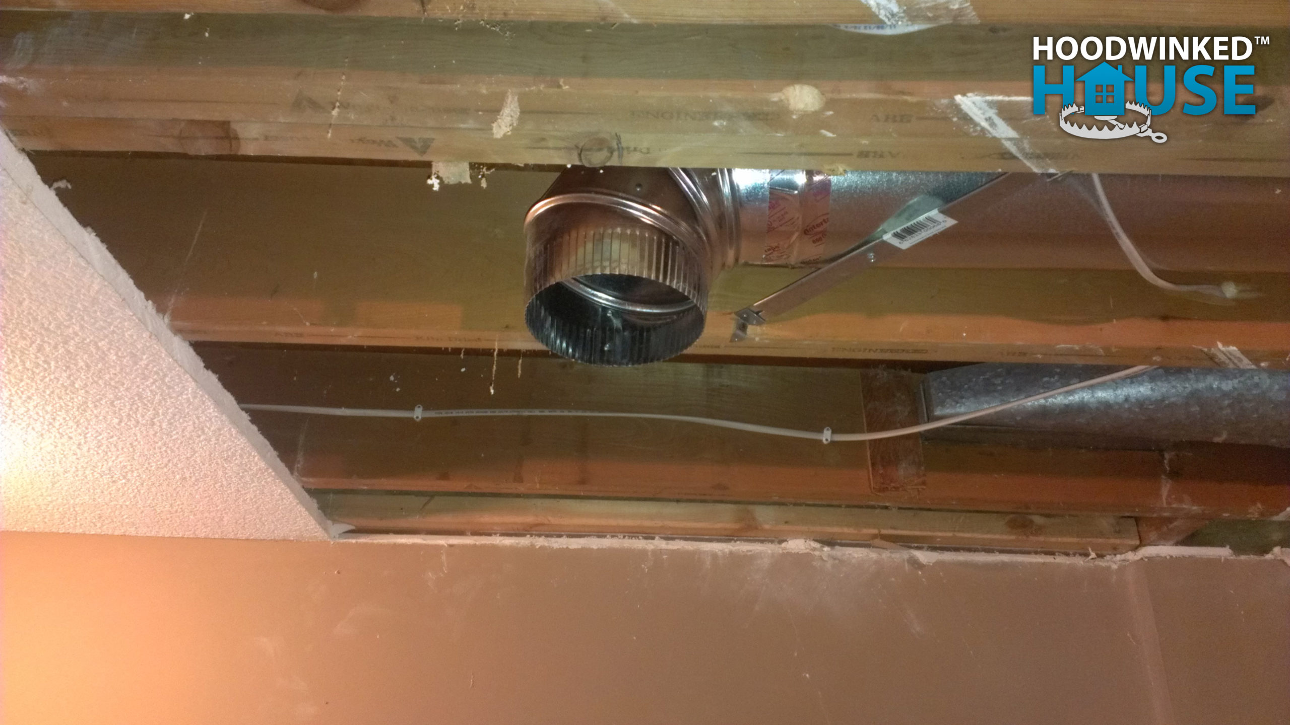 An basement ceiling air duct branch ends in an elbow.