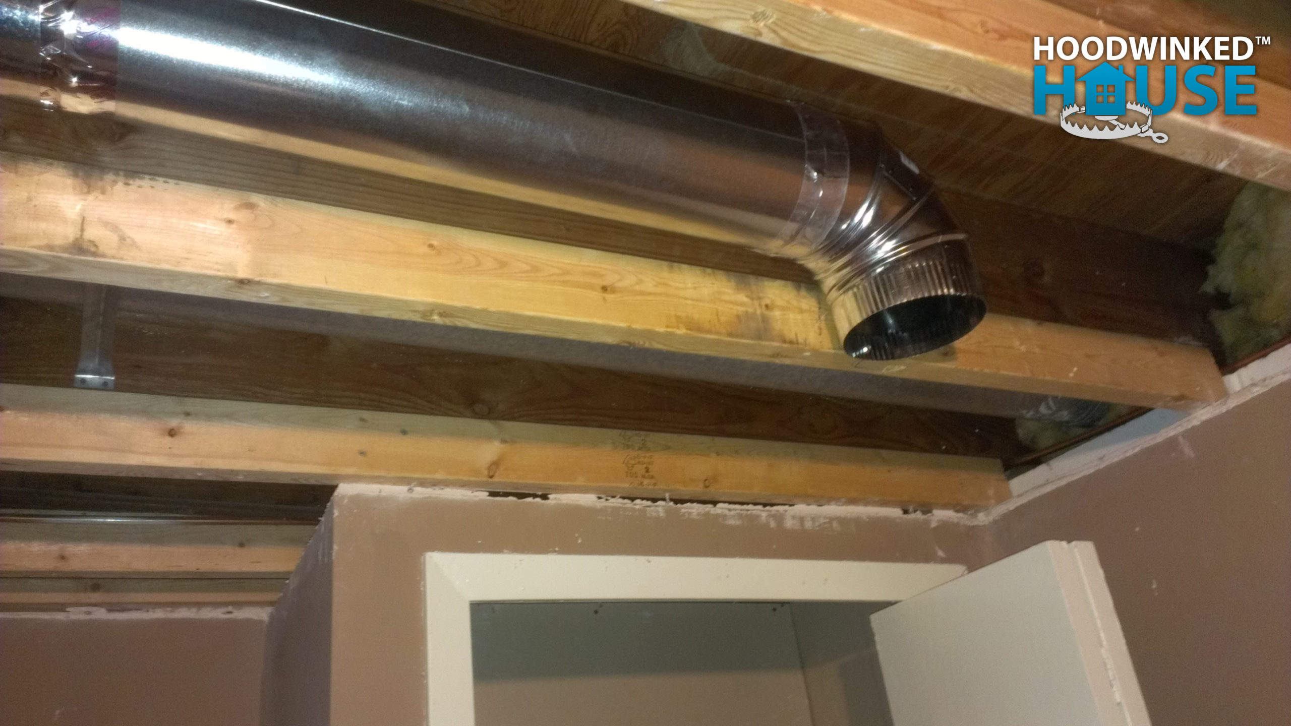 An basement ceiling air duct branch ends in an elbow.