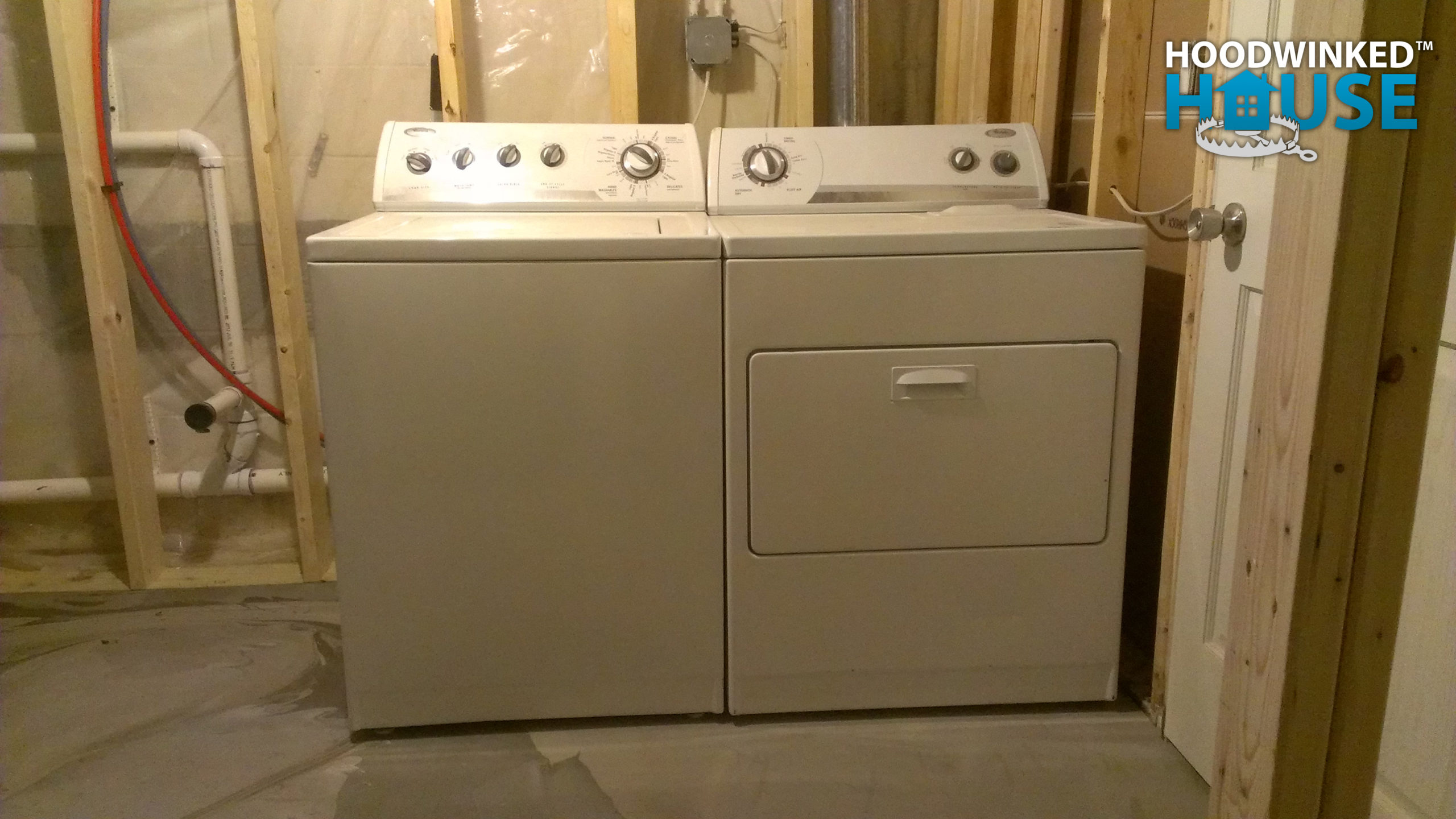 A washer and dryer sit in an unfinished basement laundry room.