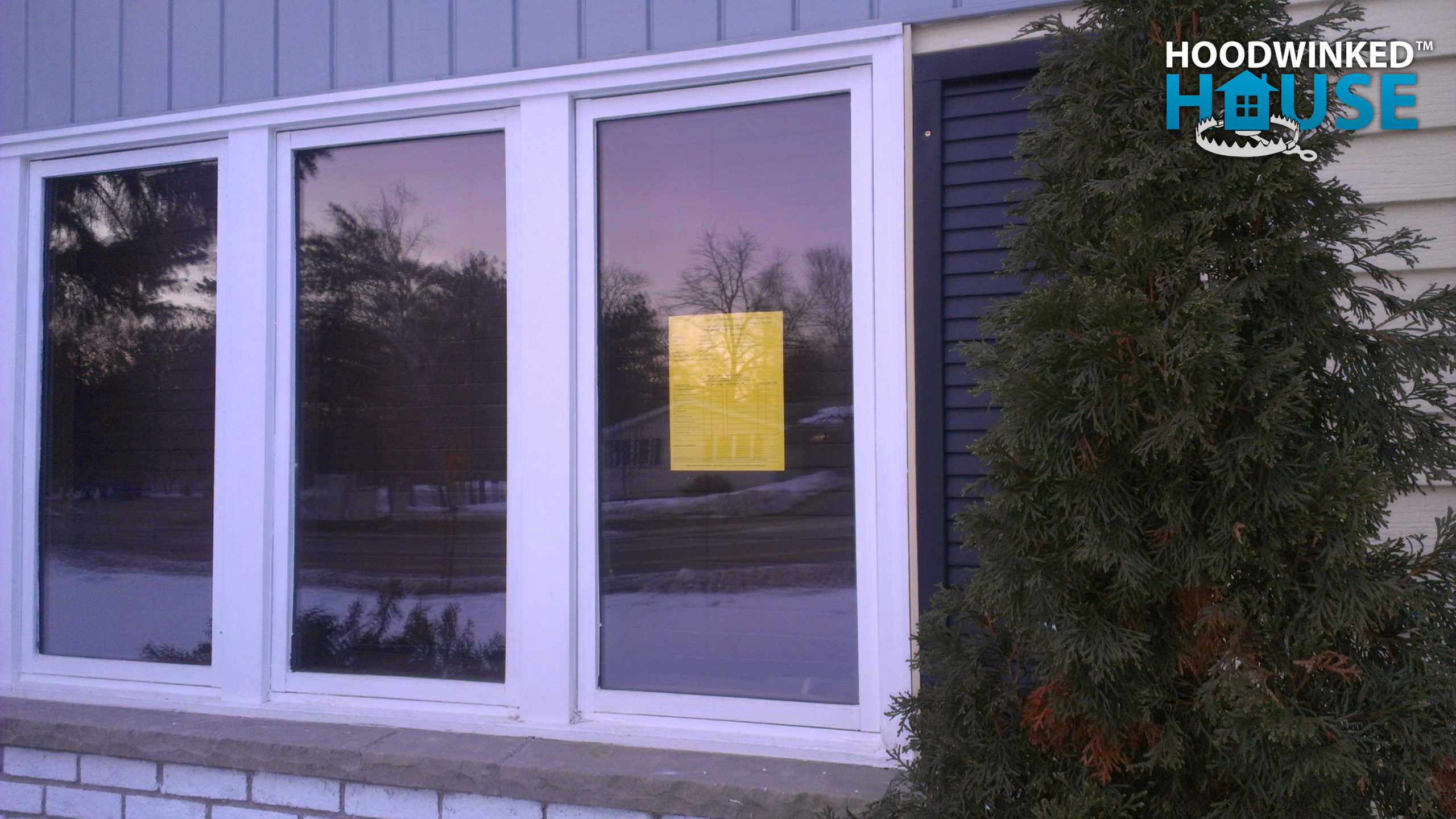 A yellow building permit inspection card hangs in the window near the front door of a house that is being remodeled.