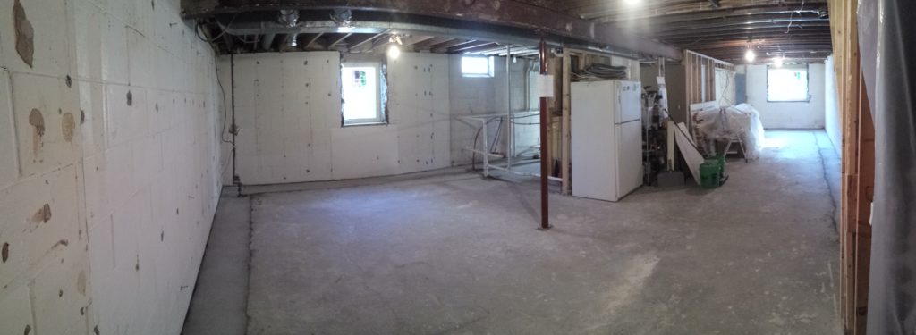 An unfinished basement with new drain tile around the perimeter and new windows.