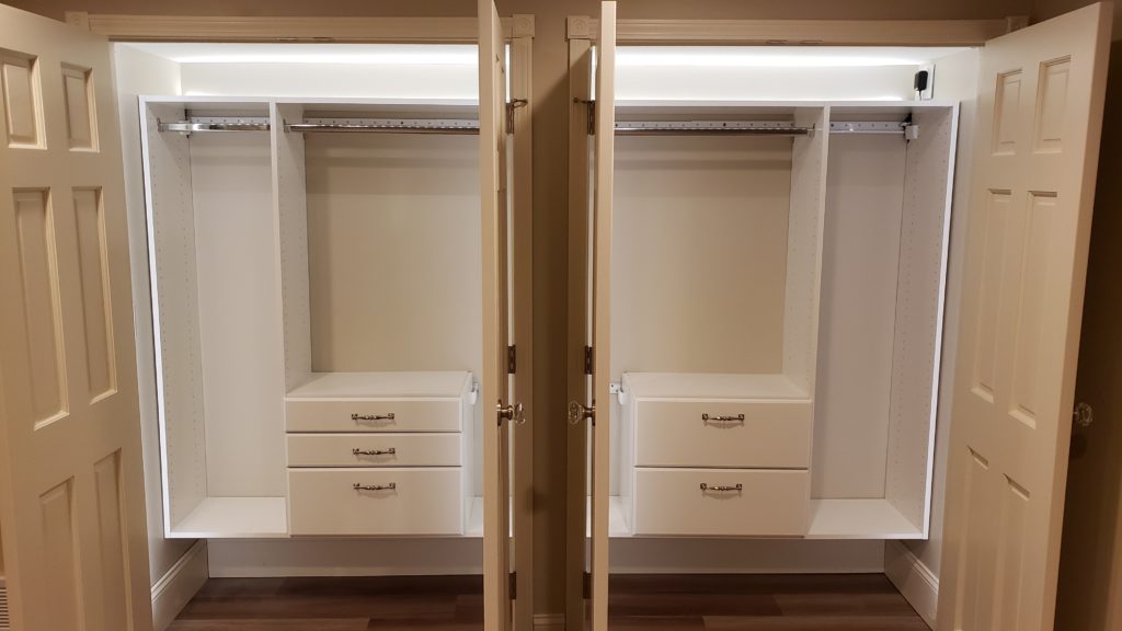 Two empty closets with the doors open showing closet organizing systems and bright LED lighting.