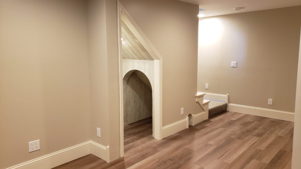 The underside of a staircase has an arched support, and is finished with textured paneling.