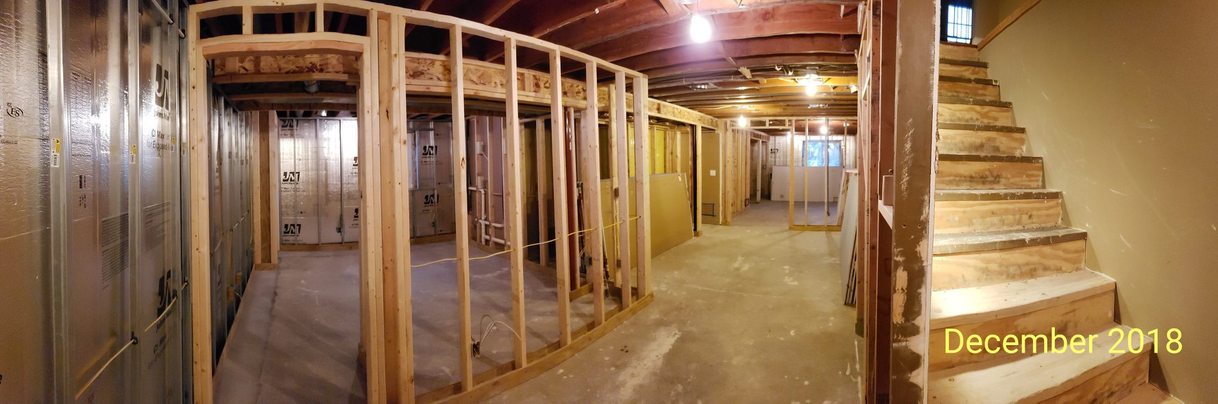 Panoramic view of an unfinished basement with bare stud walls as seen in December 2018.