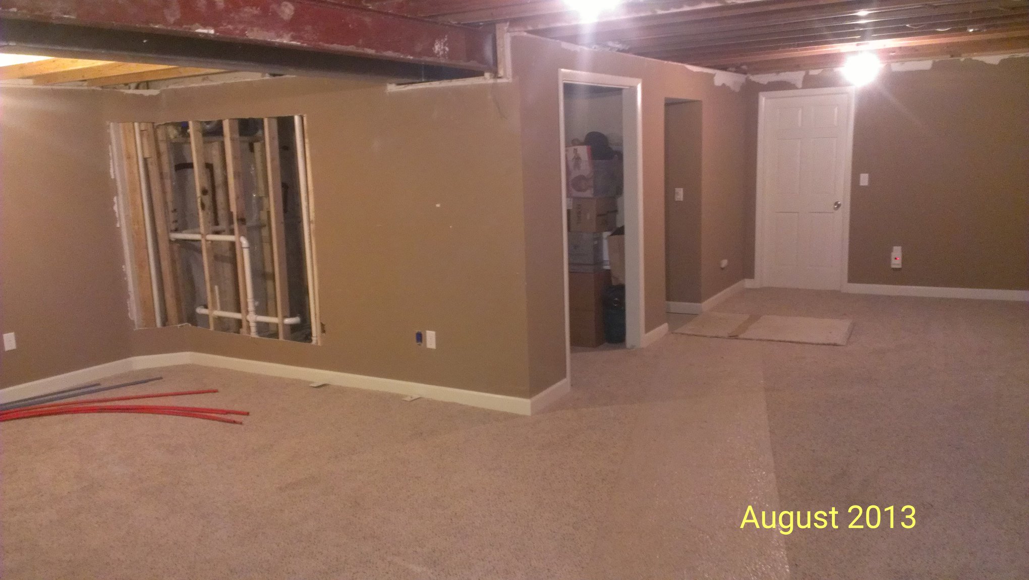 A finished basement with partially demolished drywall and a soffit dated August 2013.