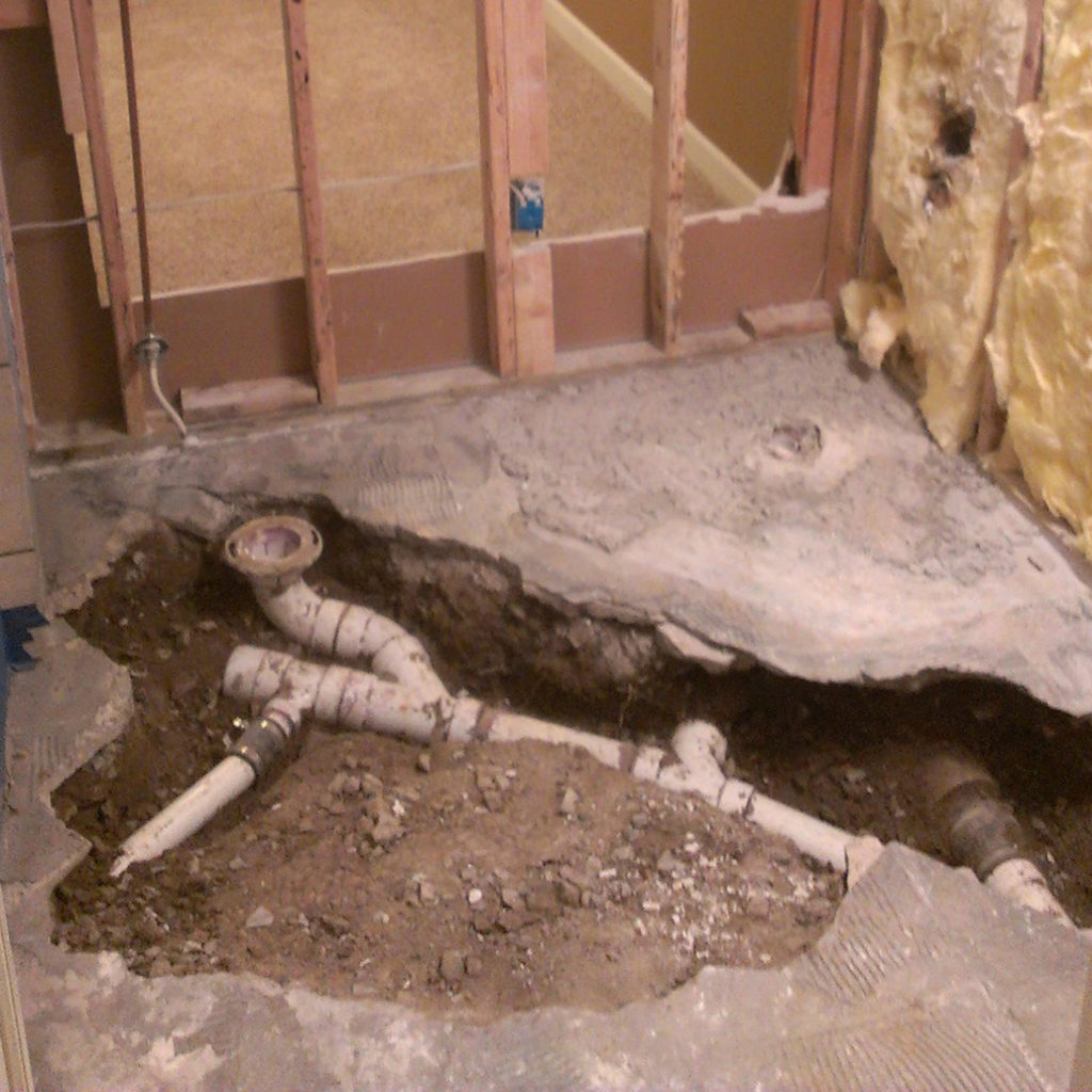 Partially excavated drain pipes in a basement.
