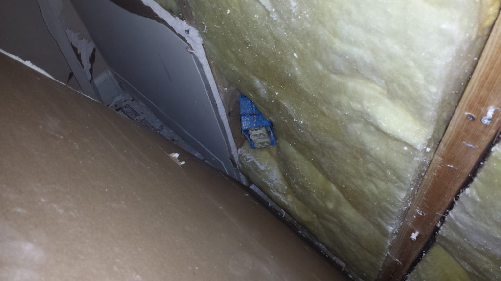 An outlet junction box has been bent backwards and covered with drywall.