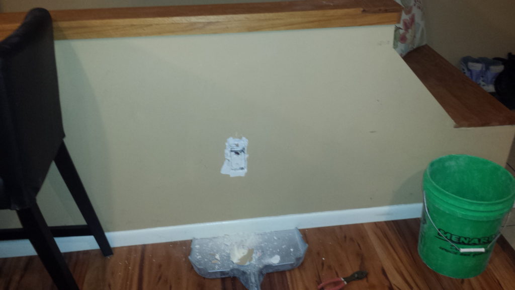 Stairwell half wall with an electrical outlet concealed by drywall mud.