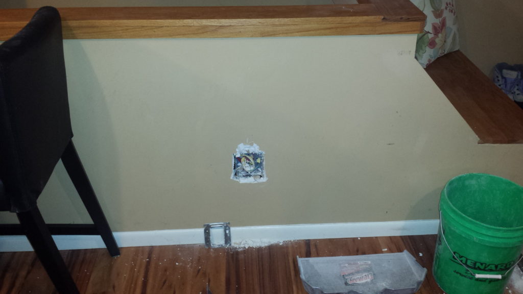 Stairwell half wall with junction box filled with drywall mud.