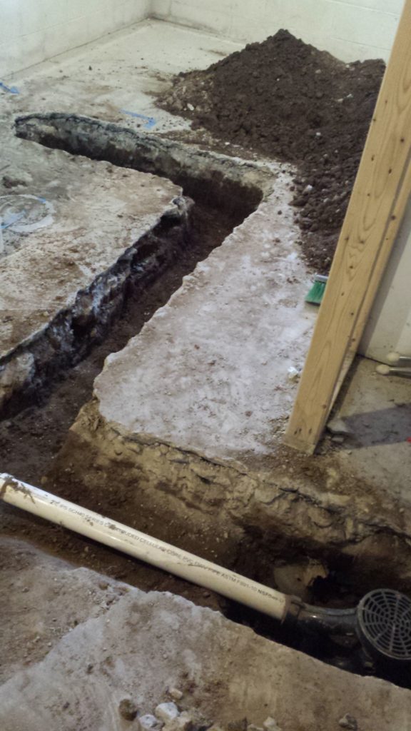 Excavated trench in a basement for underground drain pipes.