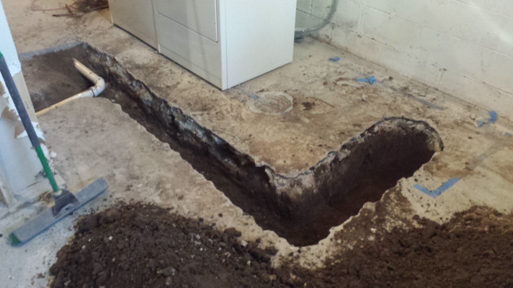 Excavated trench in a basement for underground drain pipes.