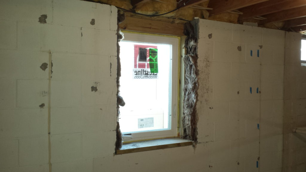Anew window is added to a basement with a window well.