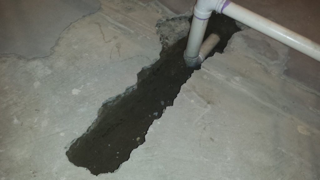 Trench in a basement floor for new underground plumbing.