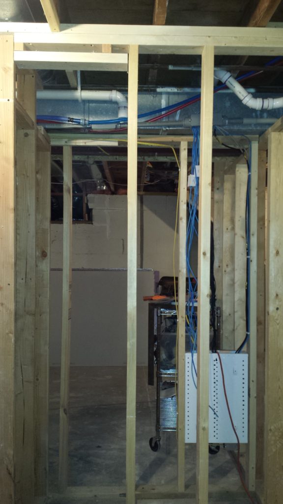 Stud wall framing for a linen cabinet in a basement bathroom.