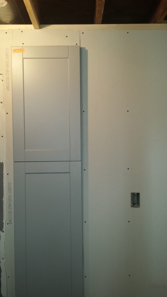 Linen cabinet inset in a wall in a basement bathroom.