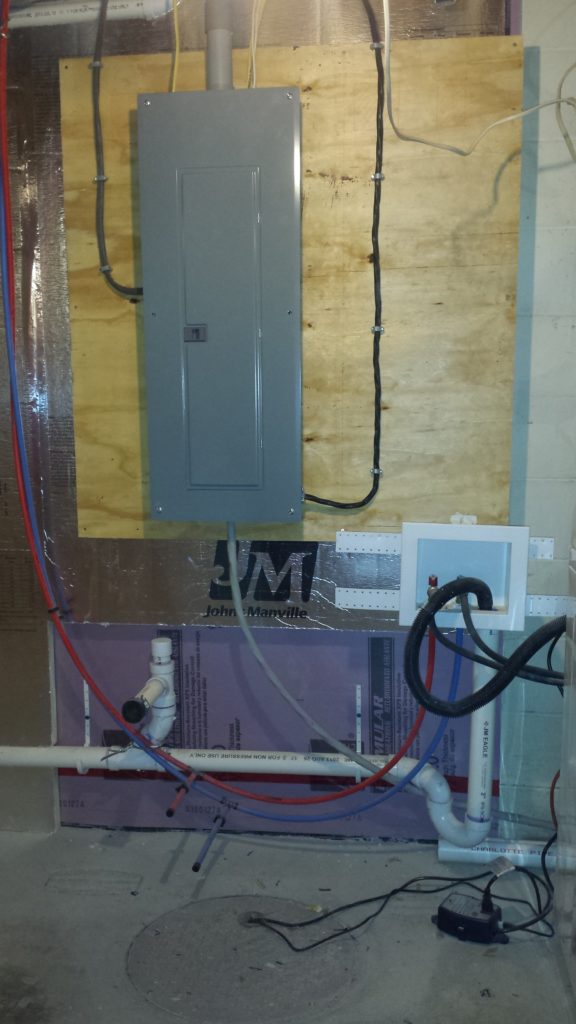 Roughed in electric service panel in a basement with temporary power connected.