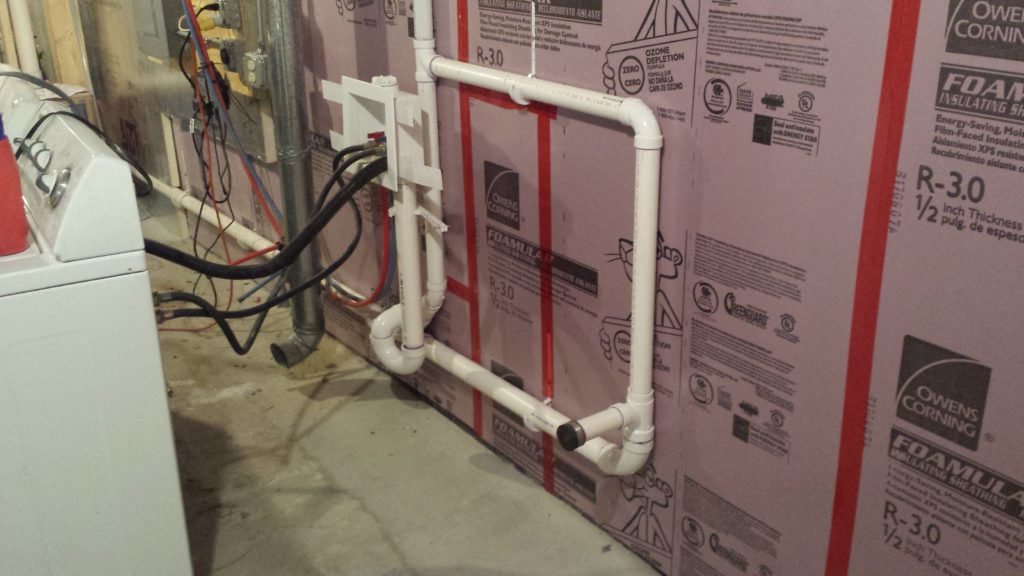 Foamboard insulation cut to match the shape of pipe hangers on a basement wall.
