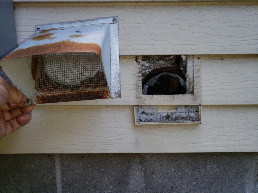 A rusted fresh air intake, removed from the exterior of a house.