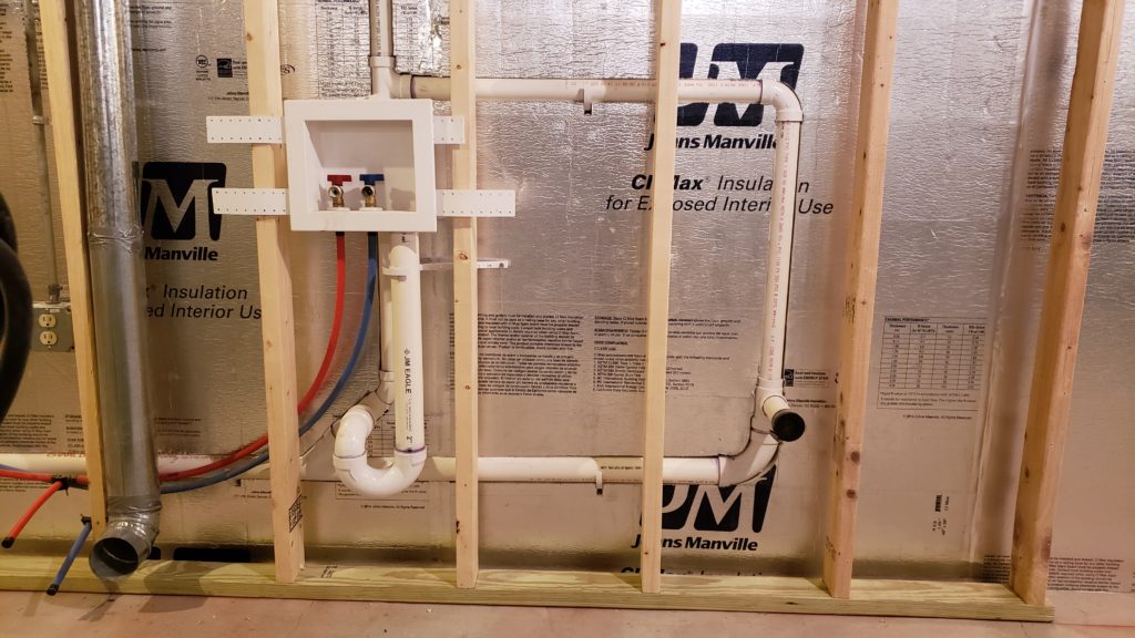 Framing for a basement laundry room wall with roughed in plumbing.