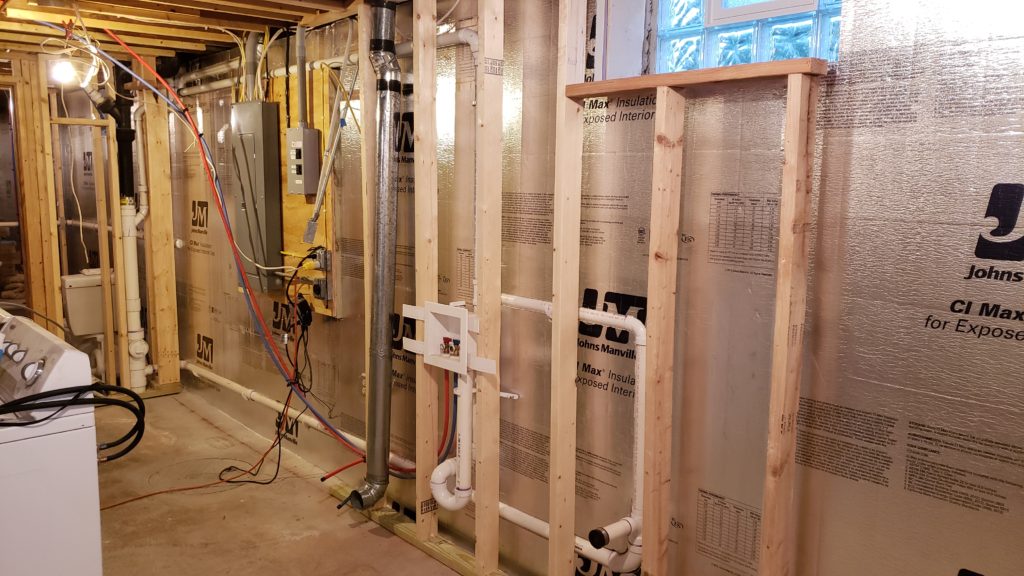 Framing for a basement laundry room wall with roughed in plumbing.