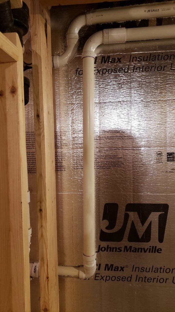 PVC plumbing vent pipes in a basement.