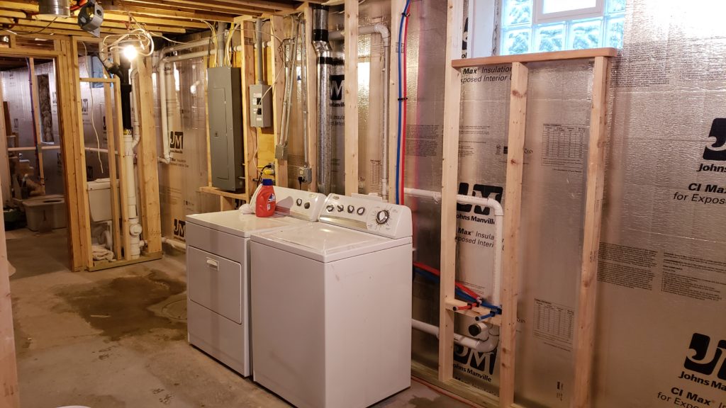 Laundry machines connected to new plumbing in an roughed in basement.