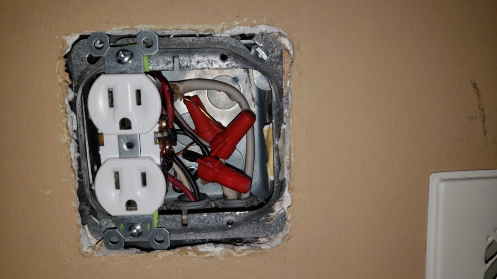 A junction box with one outlet installed in a finished wall.