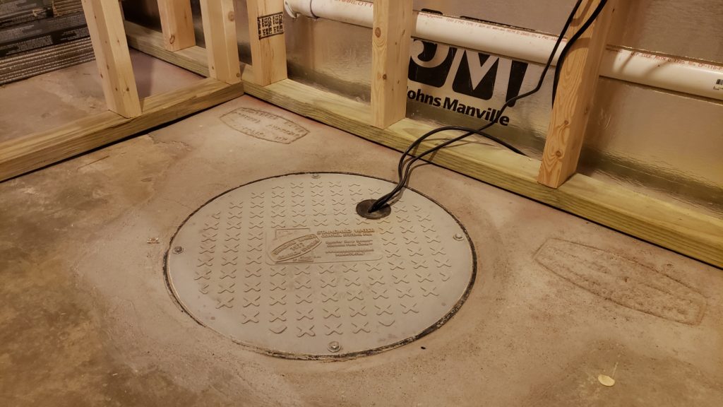 Sump pit cover as part of a drain tile system in a basement.