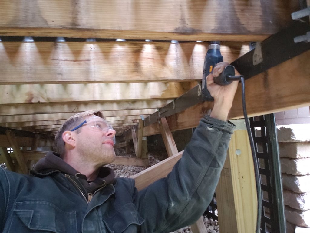 Using a drill beneath a deck.