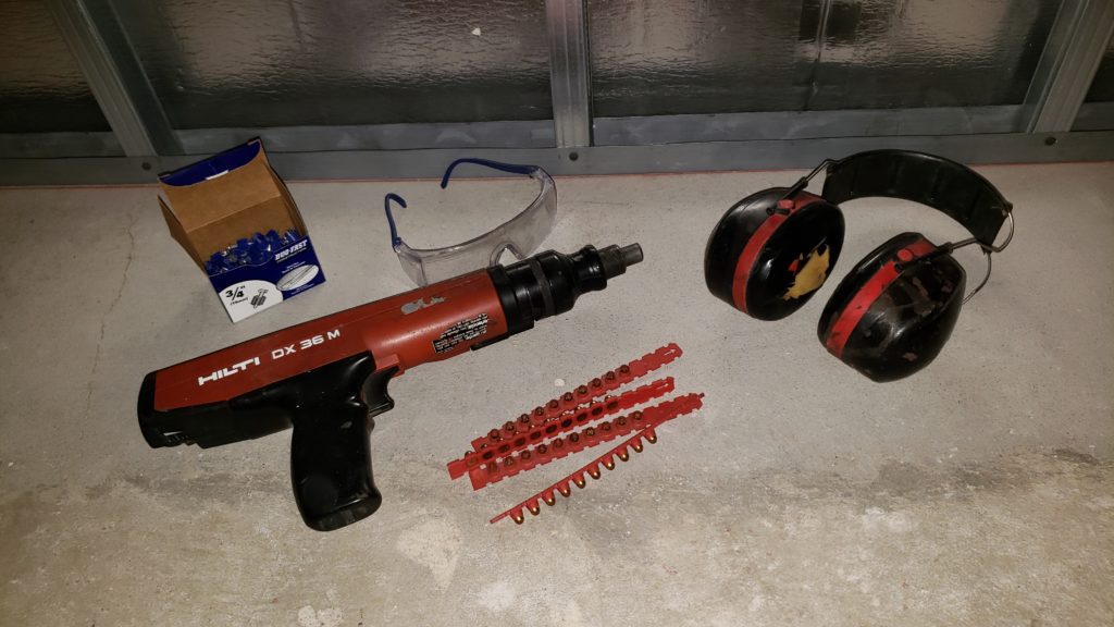 Ramset nail gun with concrete nails, safety glasses, and ear muff hearing protection.