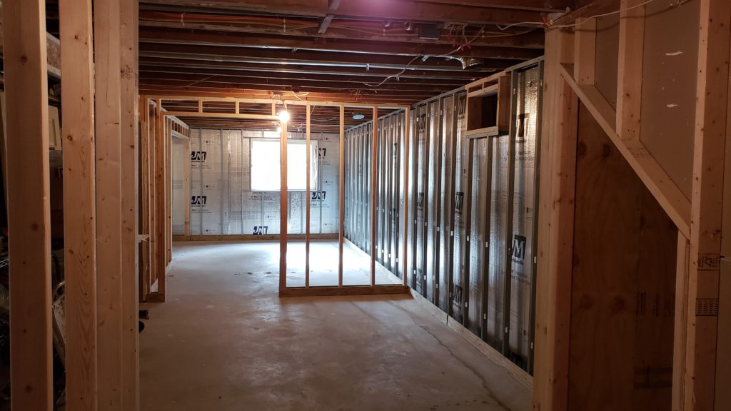 Framing in a basement is a mixture of metal stud walls on the perimeter and wood stud walls in the center.