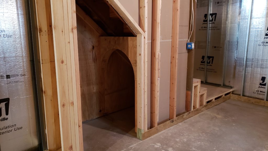 Rough framing of an archway beneath a basement staircase.