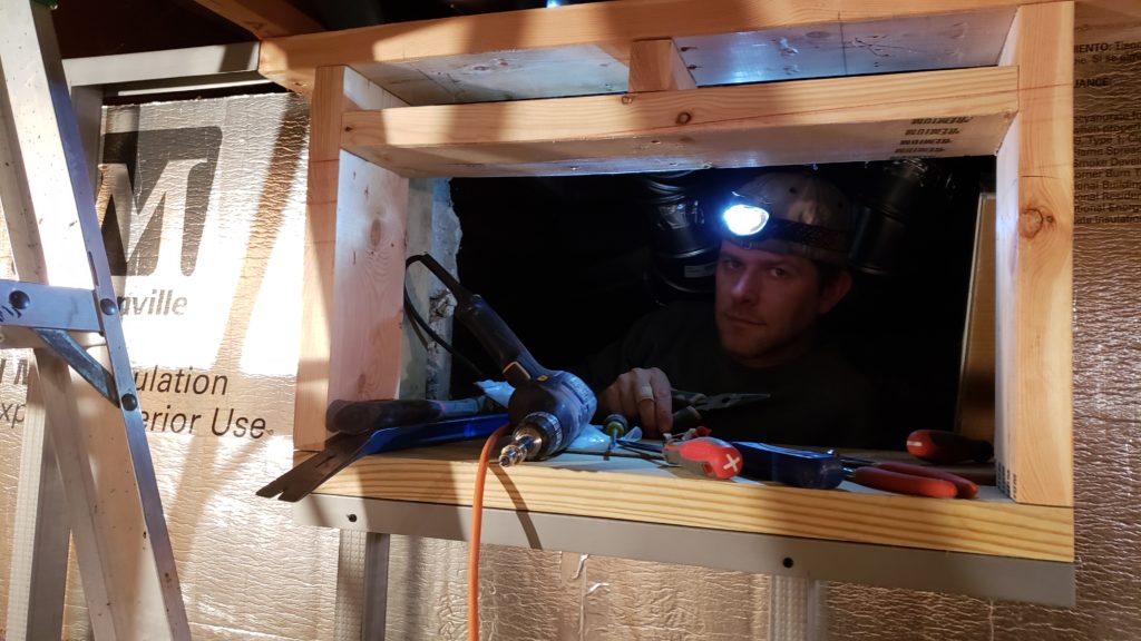 Working in a basement crawlspace while wearing a headlamp.
