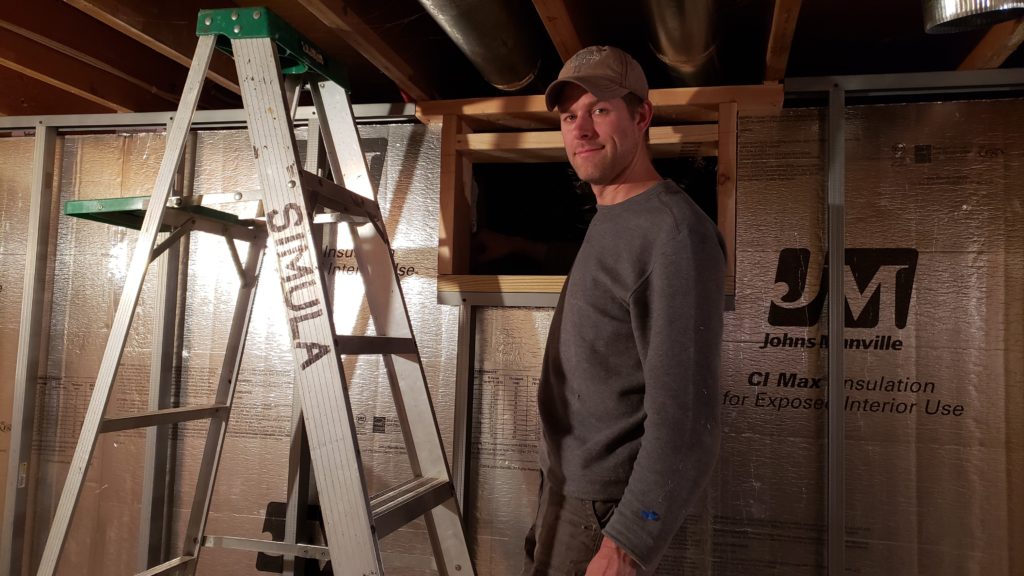 Using a ladder to climb through a small basement window into a crawlspace.
