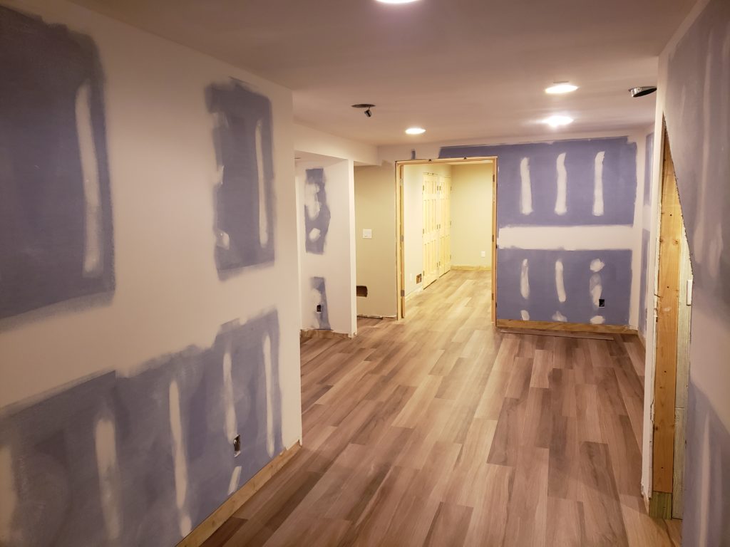 Wood grain vinyl flooring planks in an unfinished basement.