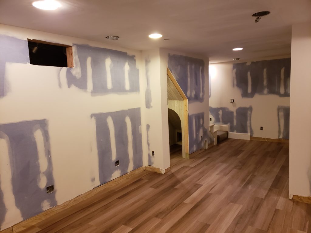 Wood grain vinyl flooring planks in an unfinished basement.