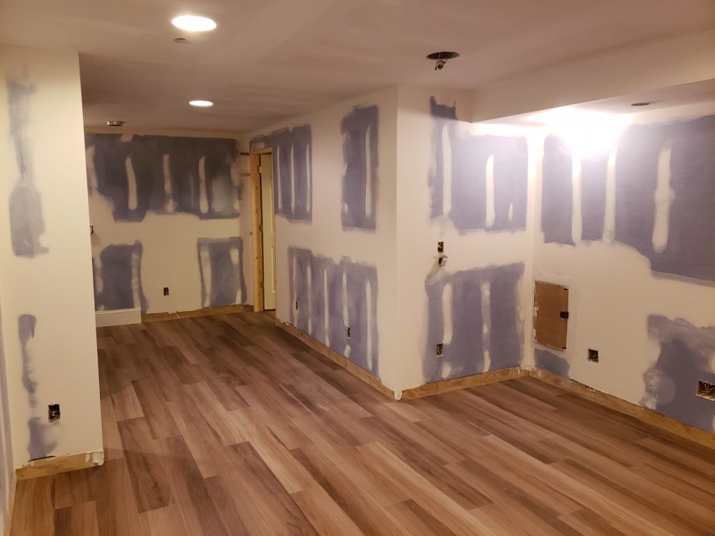 Wood grain vinyl flooring planks in an unfinished basement.