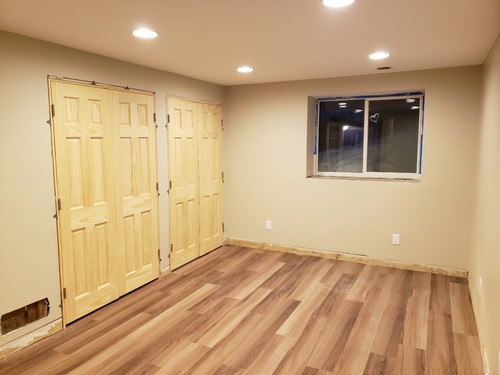 Two sets of unfinished double closet doors installed in a bedroom.