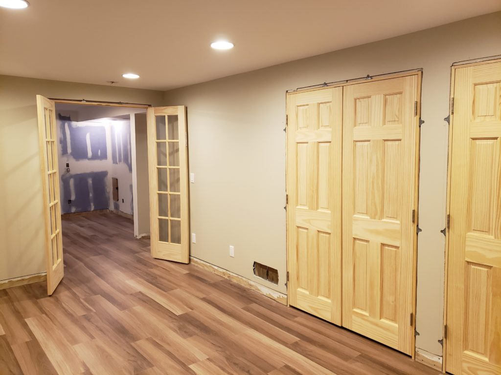 Unfinished French doors and double closet doors installed in a bedroom.