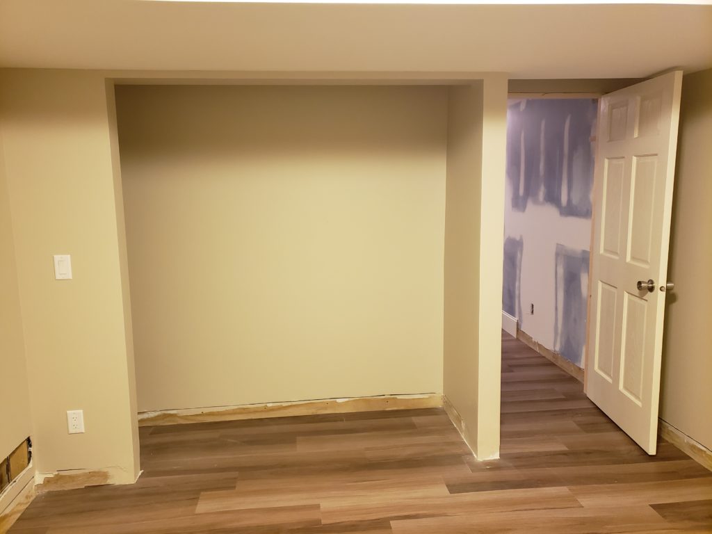 Finished basement bedroom closet with out doors or shelving.